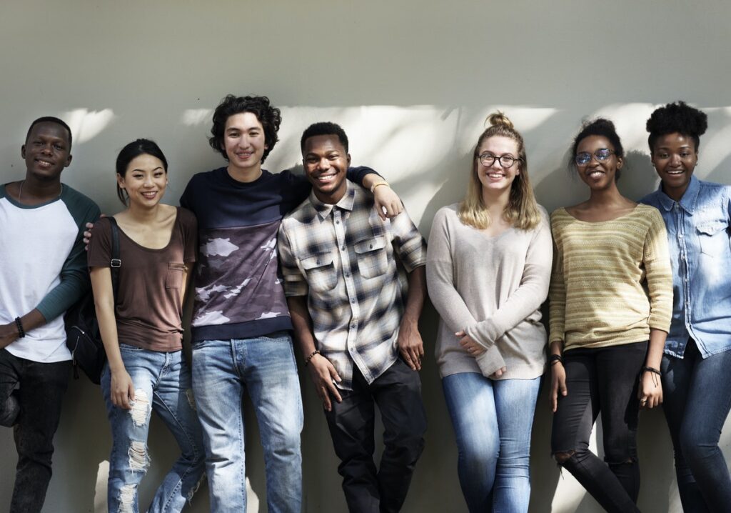 A diverse group of young adults huddled together, engaged in a discussion about faith and outreach, highlighting research on young adults and evangelism.